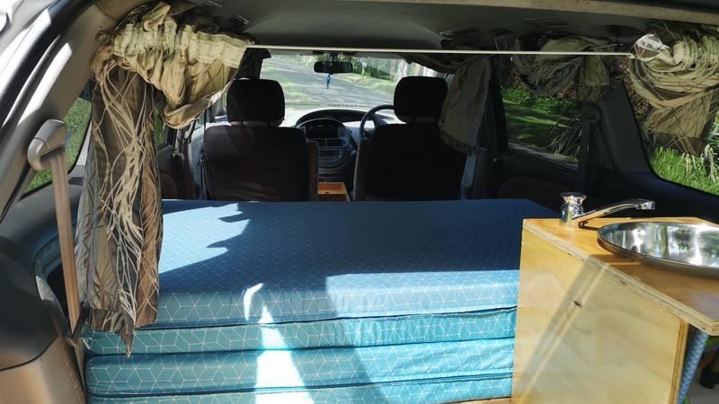Inside the FBE338 campervan looking forward over the bed to the front seats and dashboard