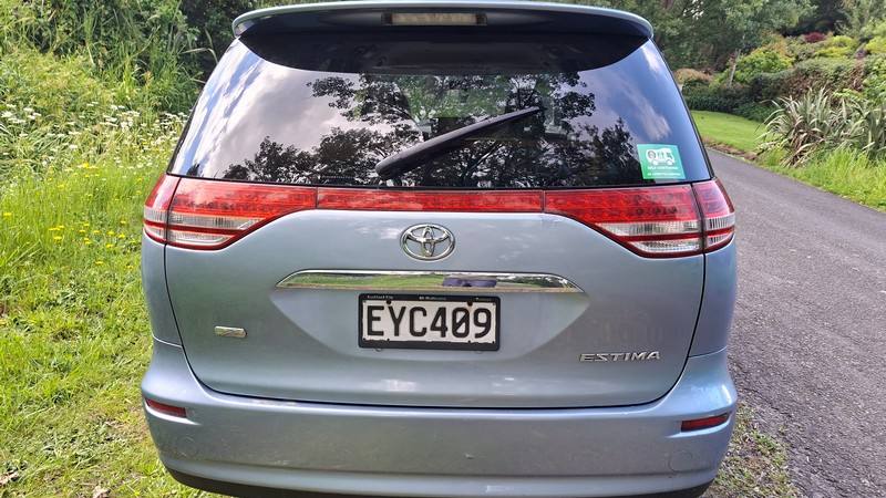 Back of the blue Toyota Estima campervan with registration EYC409 and the self-contained sticker