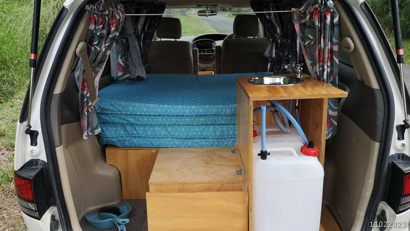 Tailgate open on the JBB773 campervan, showing the bed, sink unit and fresh water container
