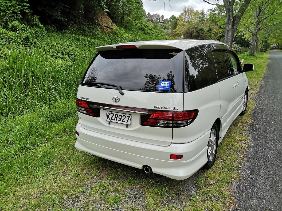 Rear three-quarter view of the white Toyota Estima campervan KZR927, green self-contained sticker in the window