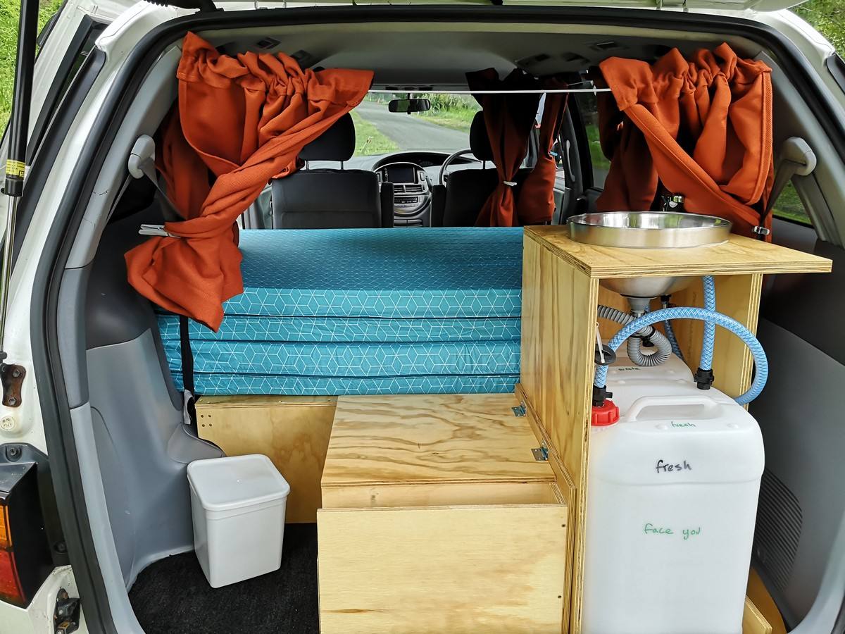 Tailgate open on the HDP33 campervan, showing the kitchen unit with sink, fresh water container and rubbish bin