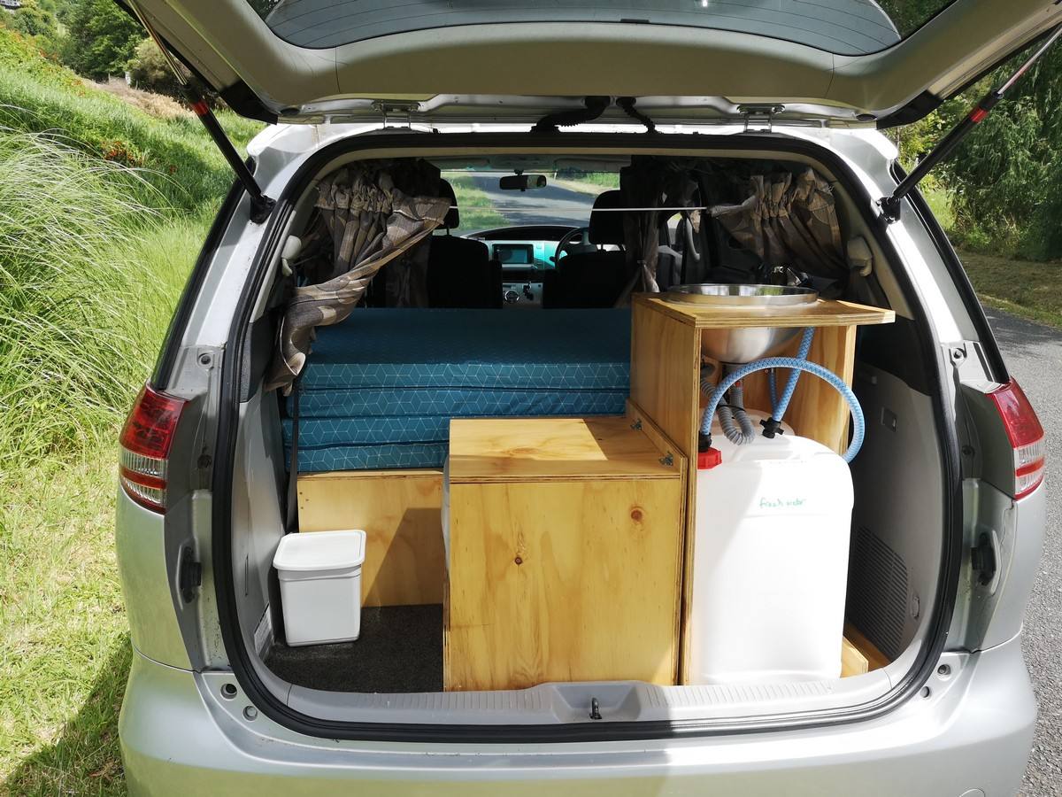 Tailgate open on the JTQ214 campervan, showing the kitchen unit, water container, portable toilet and bed