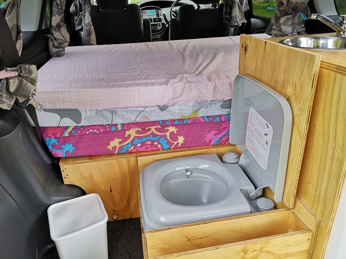 Portable toilet in the JDP67 campervan, stowed beside the bed under the sink unit