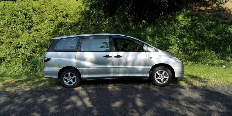 Side view of the silver Toyota Estima campervan GBB26 on a quiet country road