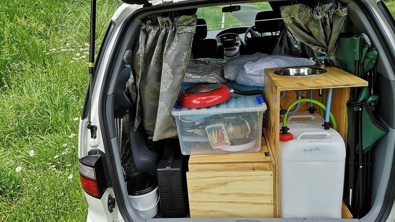 Tailgate open on the FJD528 campervan, packed with the kitchen unit, storage boxes and water container