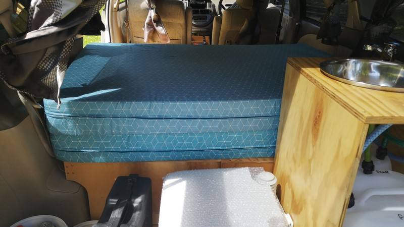 Bed cushion on the plywood base in the GQG541 campervan, sink unit alongside