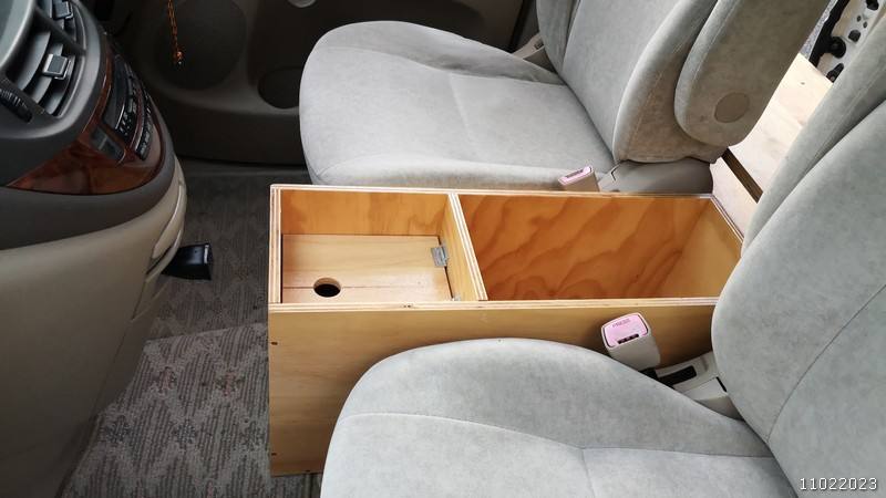 Plywood console box fitted between the front seats of the JBB773 Toyota Estima campervan