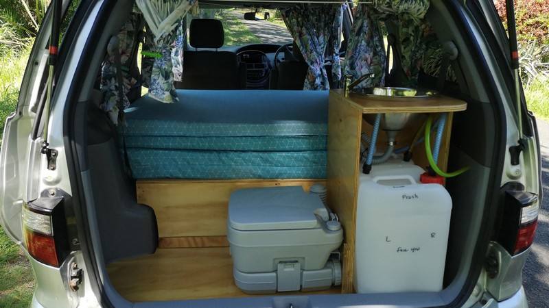 Tailgate open on the FYC899 campervan, showing the bed, portable toilet, sink unit and water container