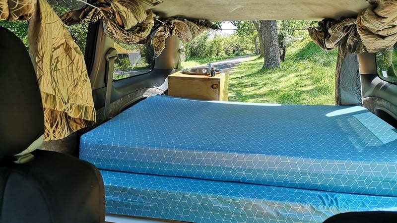 Inside the FBE338 campervan looking over the double bed to the sink unit and out through the open tailgate
