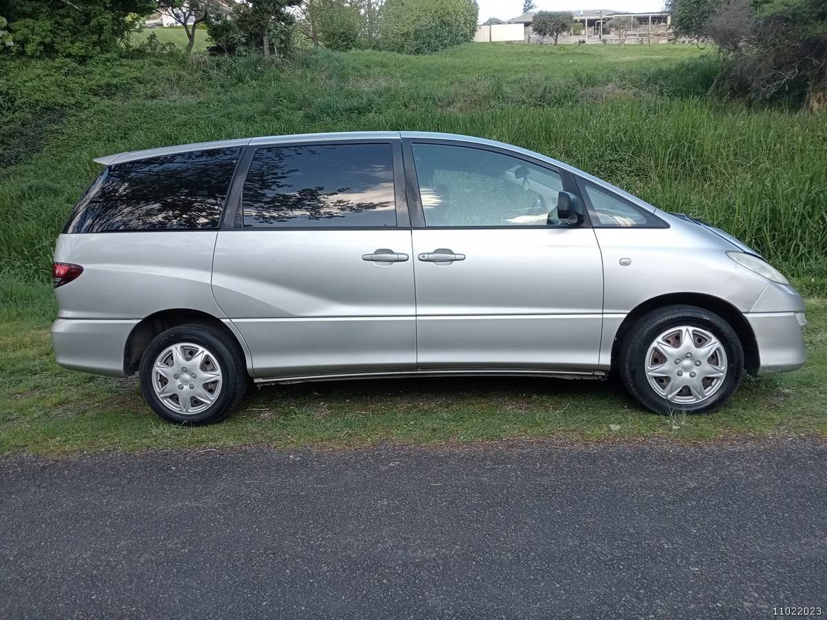 Side view of the silver 2004 Toyota Estima campervan GRH325 parked on a grass verge