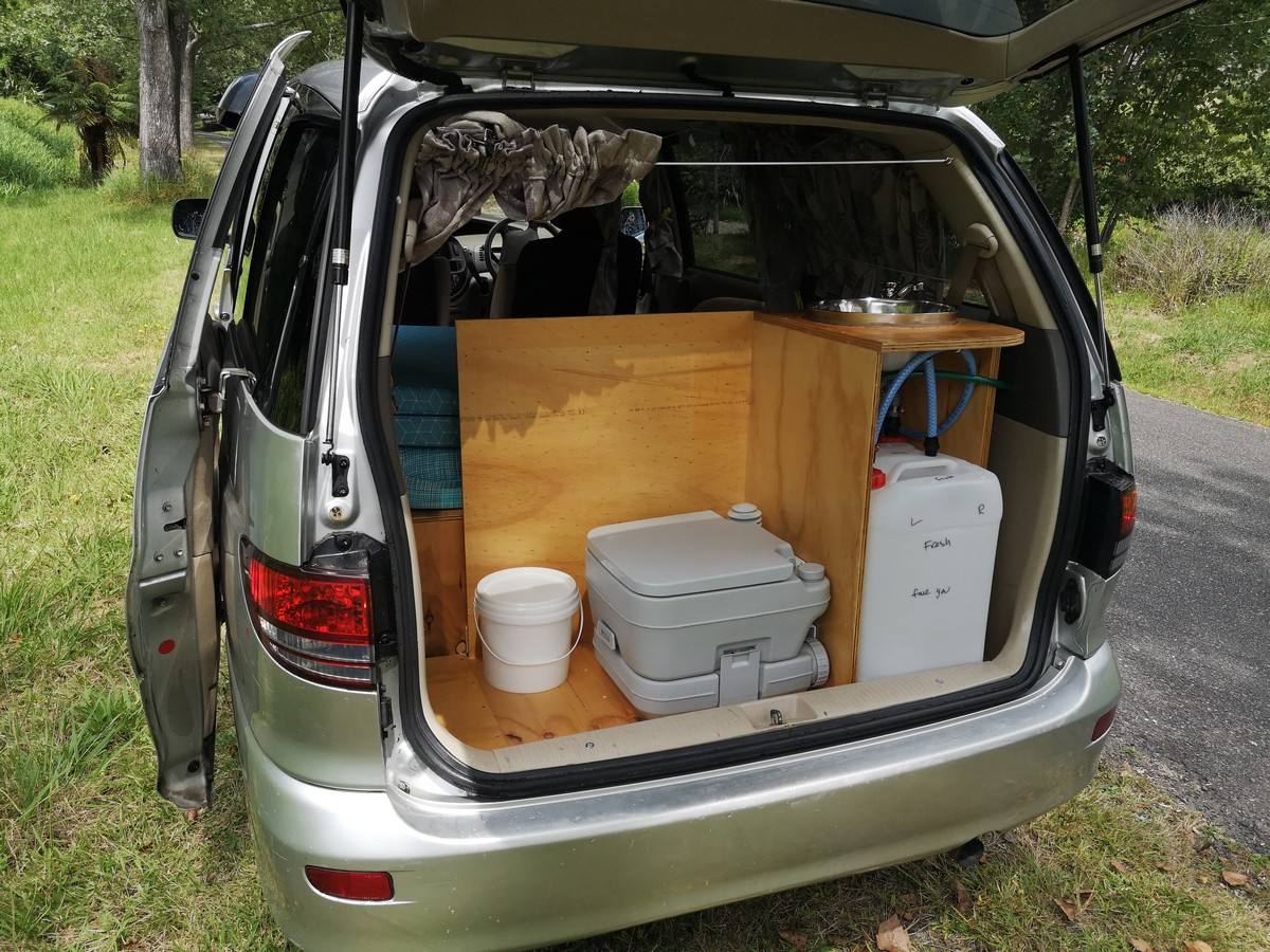 Tailgate open on the KBZ76 campervan, showing the kitchen unit, portable toilet and fresh water container
