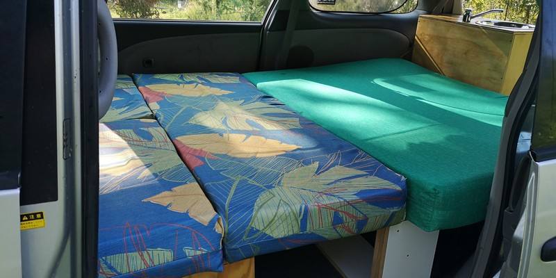 The GBB26 campervan's bed made up across the full width of the van, seat cushion alongside