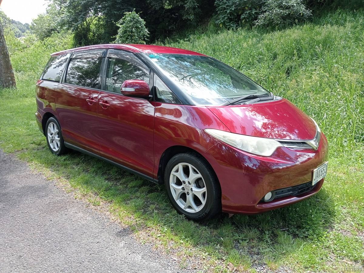 Red 2006 Toyota Estima self-contained campervan for sale, front three-quarter view from the driver's side