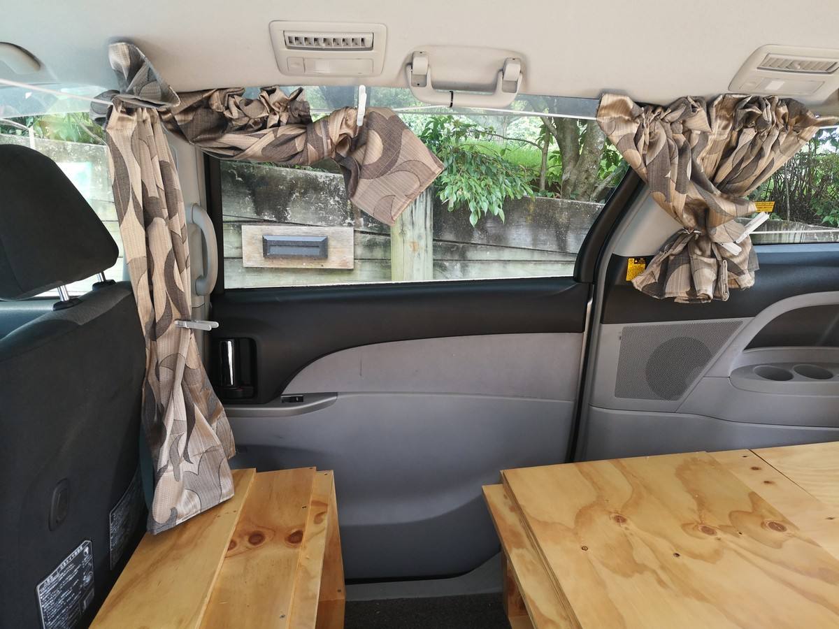Curtained side windows of the JTQ214 campervan with the plywood benches in place