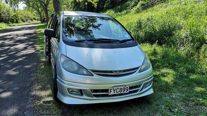 Front three-quarter view of the silver FYC899 Toyota Estima campervan on a country road