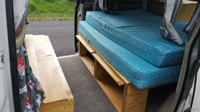 Side door open on the JBB773 campervan, bed made up with storage space below