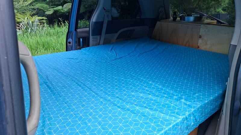 The EYC409 campervan's double bed made up across the van, sink unit at the far end