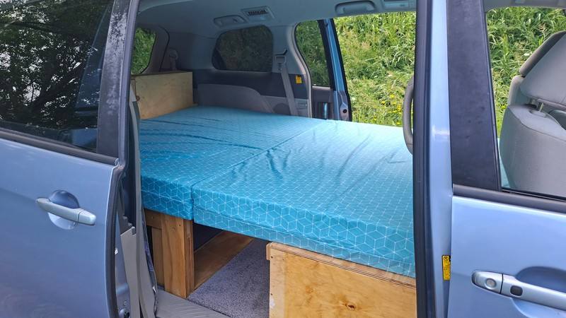 Side door open on the EYC409 campervan, double bed made up on its timber base