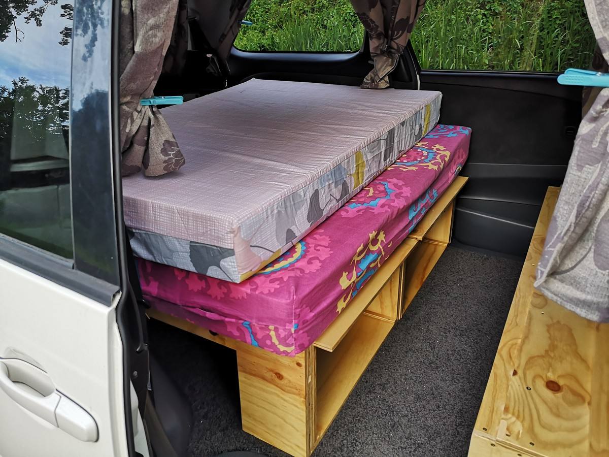 Side door open on the JDP67 campervan, mattresses stacked on the bed base with storage underneath