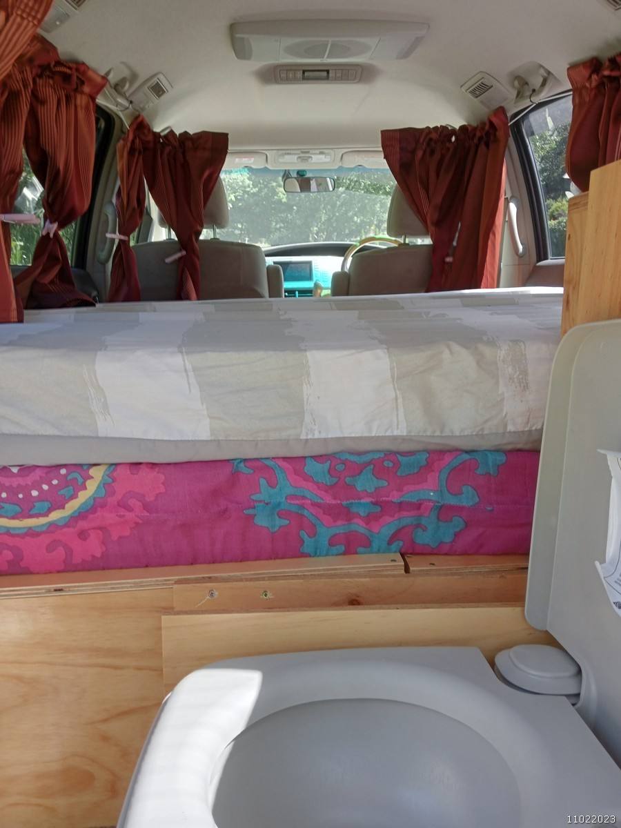 Portable toilet in the JAK653 campervan, with the made-up bed behind