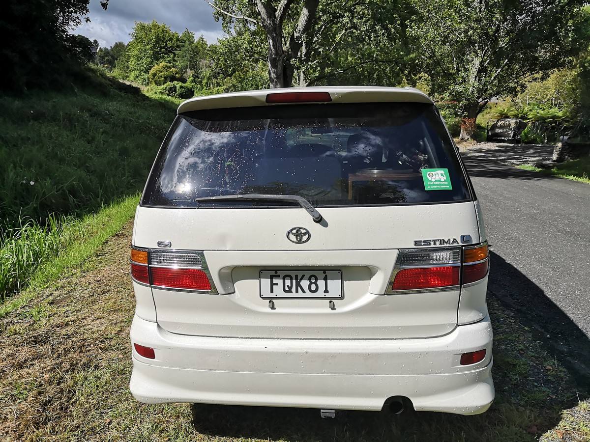 Back of the white Toyota Estima campervan with registration FQK81 and the green self-contained sticker