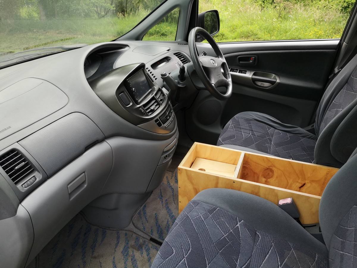 Driver's seat and dashboard of the HDP33 Toyota Estima, with the plywood console box between the front seats