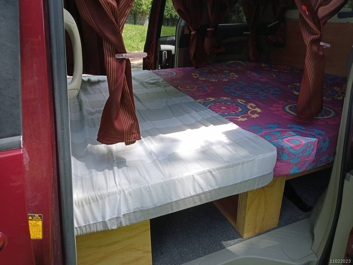 Bed being made up in the JAK653 campervan, mattress folded back over the base