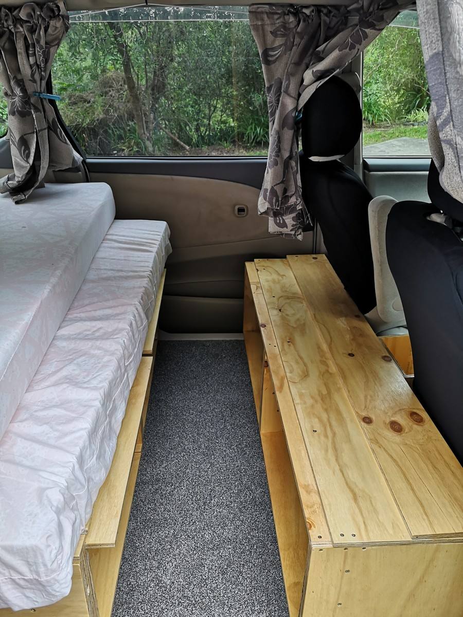 Inside the KZR927 campervan, mattress on the plywood base with the timber bench along the other side