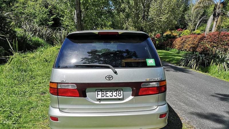Back of the silver Toyota Estima campervan FBE338, with the green self-contained sticker in the rear window