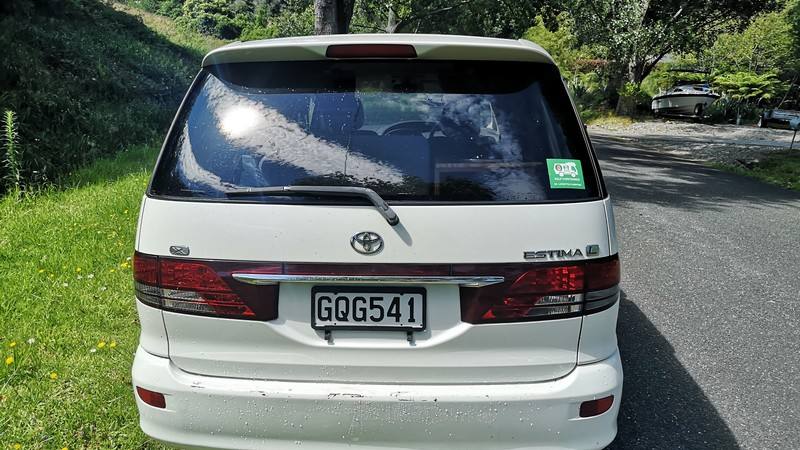 Back of the white Toyota Estima campervan with registration GQG541 and the green self-contained sticker
