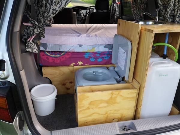 Tailgate open on the FPS382 campervan, with the sink unit, portable toilet and water container