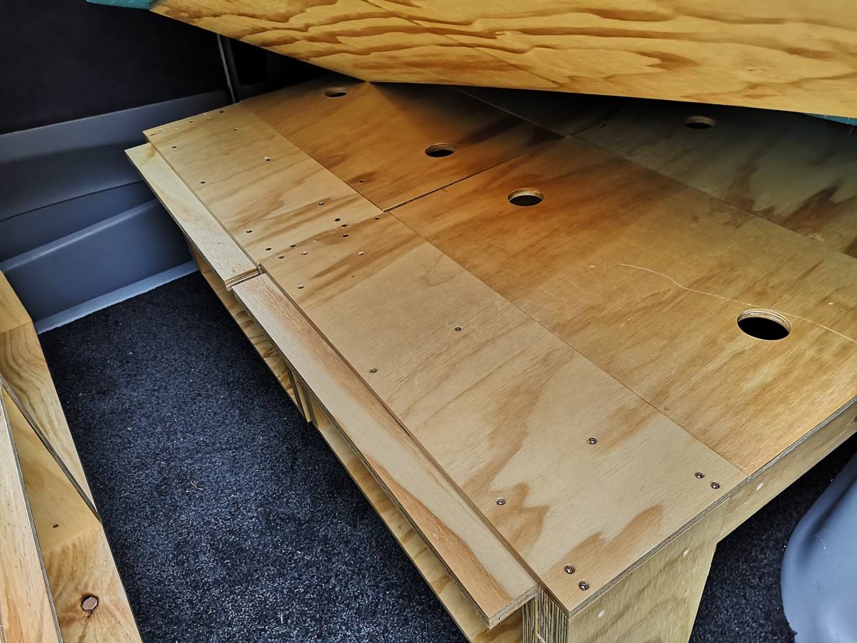 Plywood bed base of the HDP33 campervan lifted to show how the platform is built over the storage