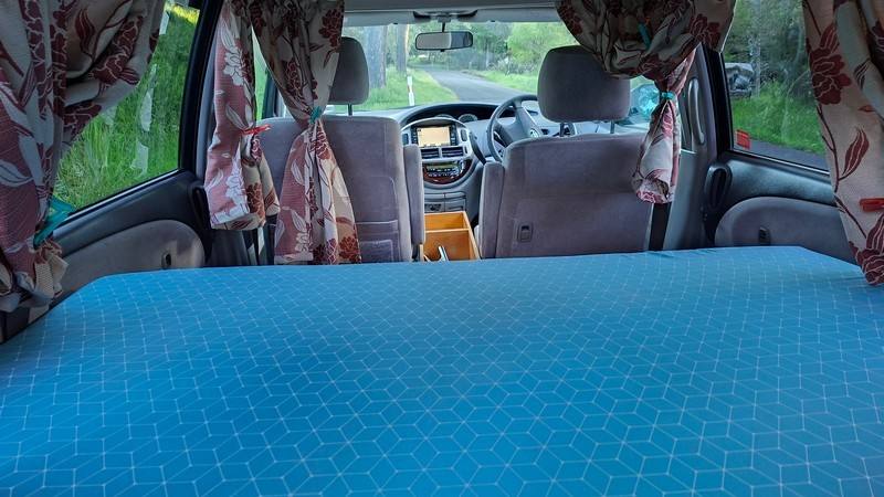 Inside the ERT416 campervan looking forward over the made-up bed to the front seats