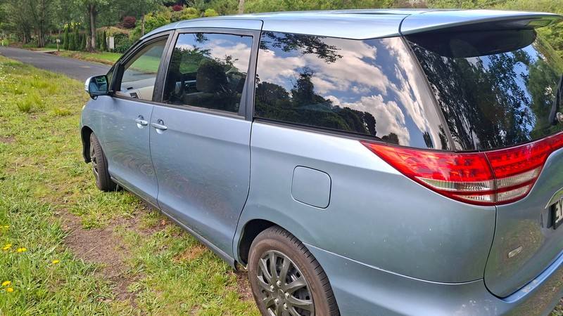 Side and rear of the blue EYC409 Toyota Estima campervan on a country road
