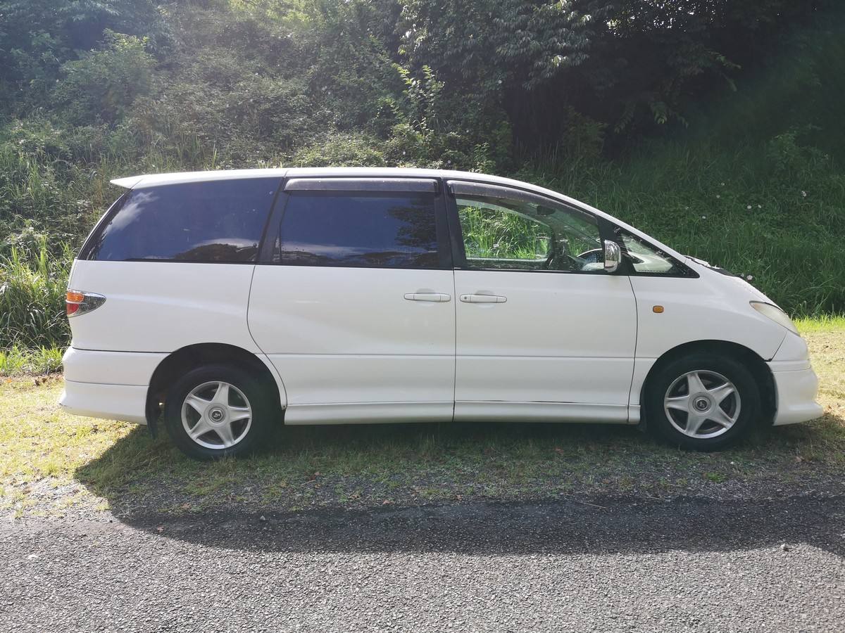 Side view of the white 2001 Toyota Estima campervan FQK81 parked on grass
