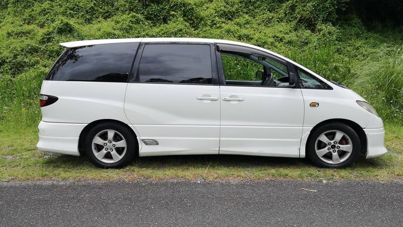 Side view of the white 2001 Toyota Estima campervan FJD528 parked on a country road