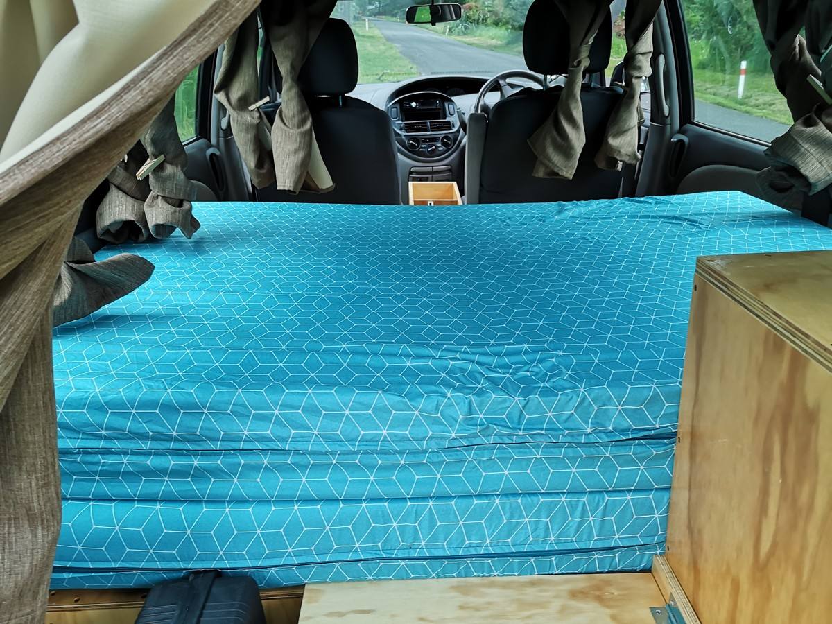 Inside the EZQ488 campervan looking forward over the made-up bed to the front seats
