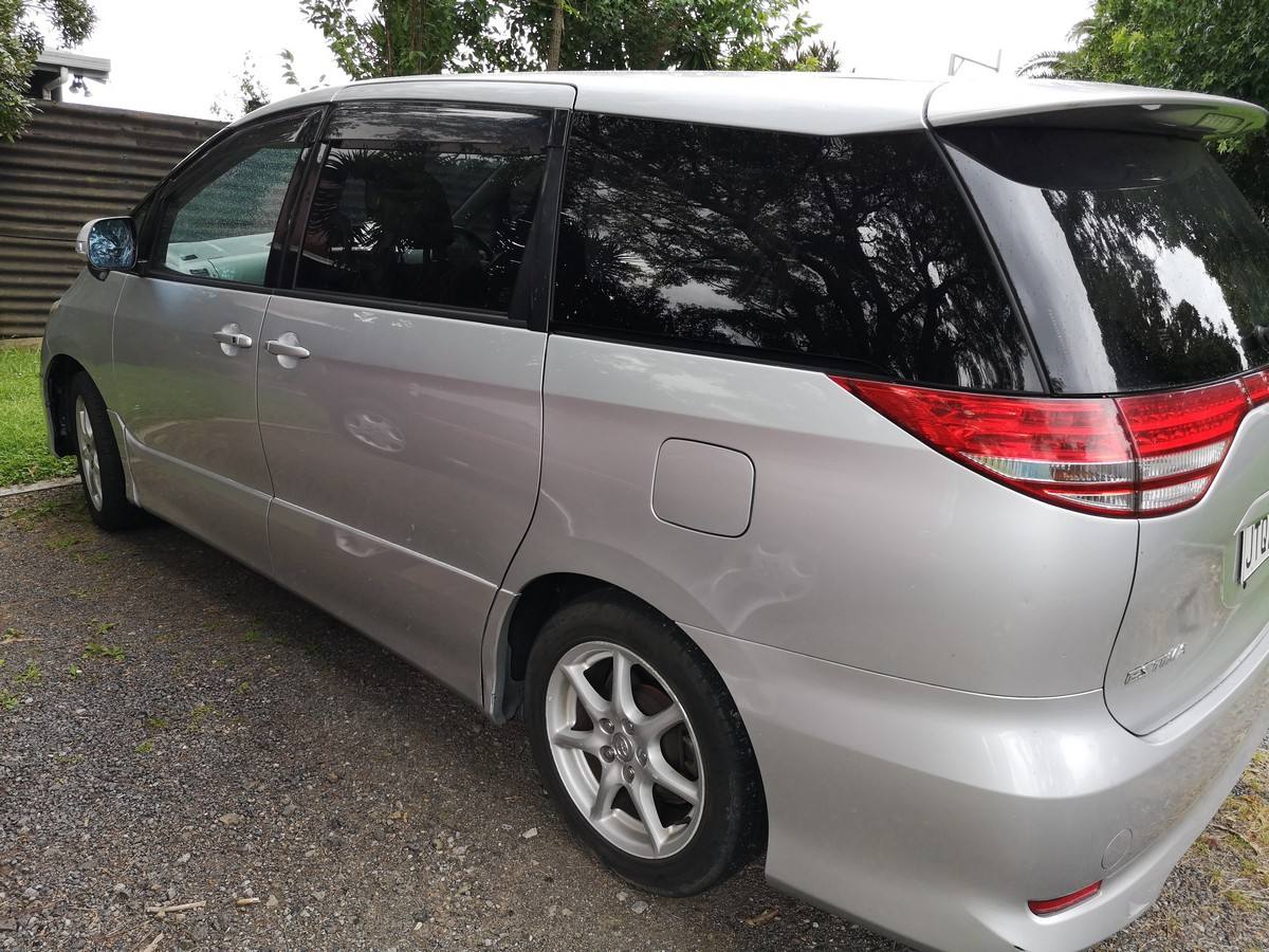 Rear three-quarter view of the silver 2007 Toyota Estima campervan JTQ214 on a gravel drive