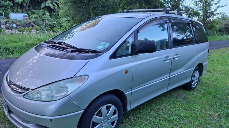 Driver's side of the silver ERT416 Toyota Estima campervan parked on grass
