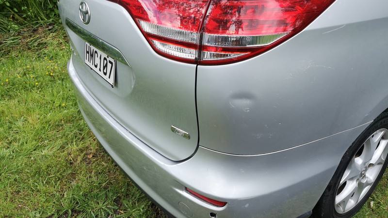 Close-up of the HMC107 Toyota Estima's rear bumper and tailgate, showing a small dent above the bumper