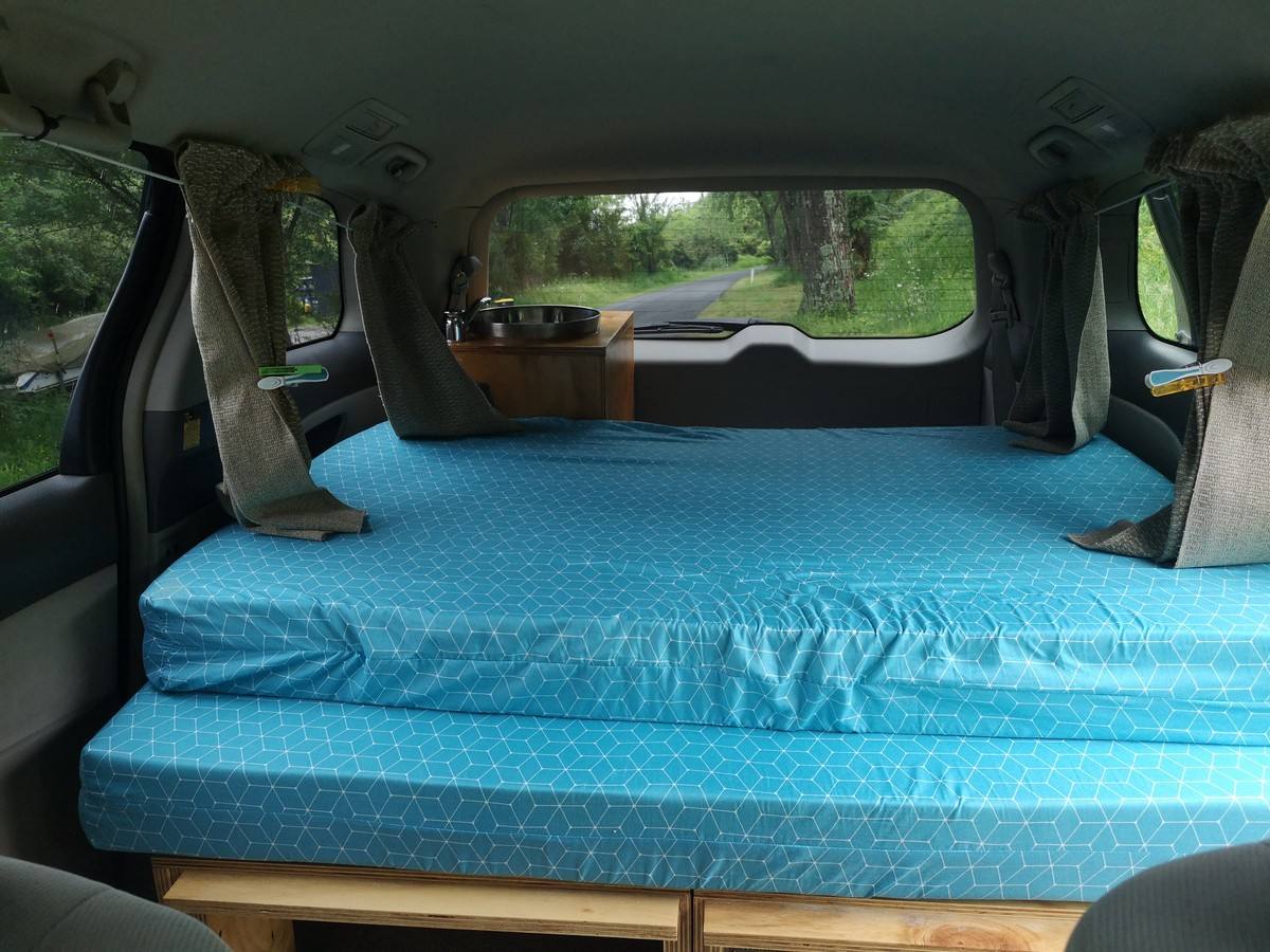 Inside the JNQ545 campervan, double bed made up looking out through the rear window