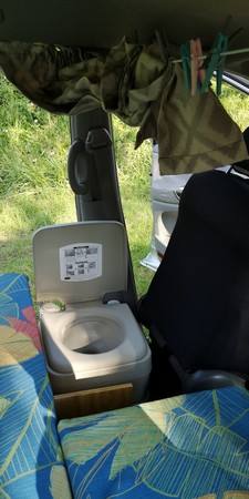 Portable toilet set up inside the GBB26 campervan next to the bed
