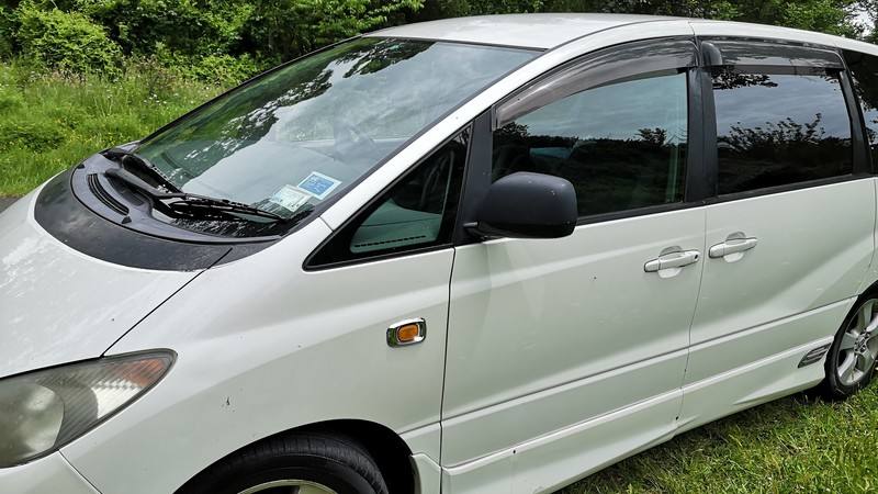Driver's side of the white FJD528 Toyota Estima campervan, front doors and windows