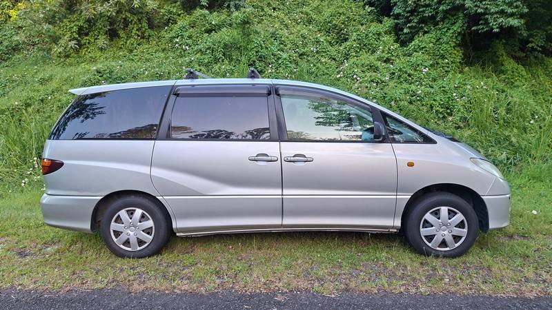Side view of the silver 2002 Toyota Estima campervan ERT416 parked on a country road