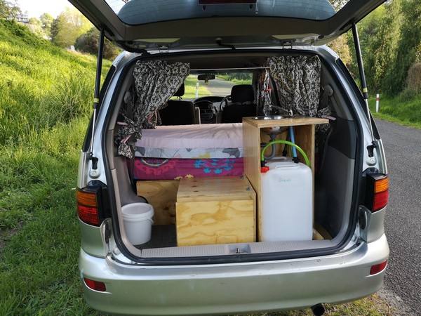 Tailgate open on the FPS382 campervan, showing the bed, kitchen unit and fresh water container