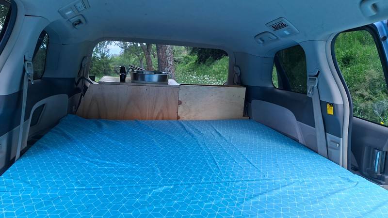 Inside the EYC409 campervan, full-width bed made up looking towards the kitchen bench