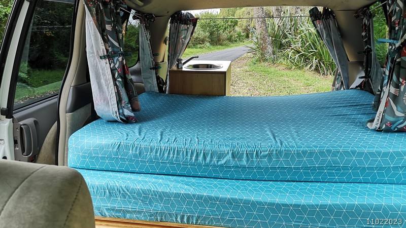 Inside the JBB773 campervan looking along the bed towards the sink unit and the open tailgate