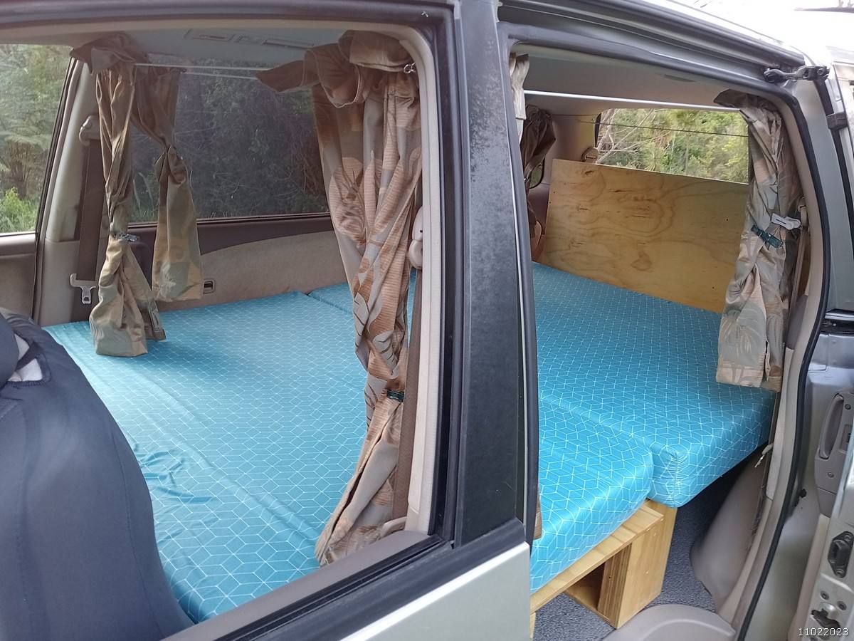 Bed made up in the GRH325 campervan seen through the open side door