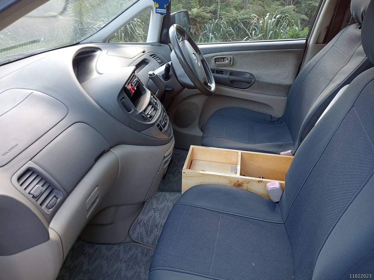 Dashboard and front seats of the GRH325 Toyota Estima, plywood console box between the seats