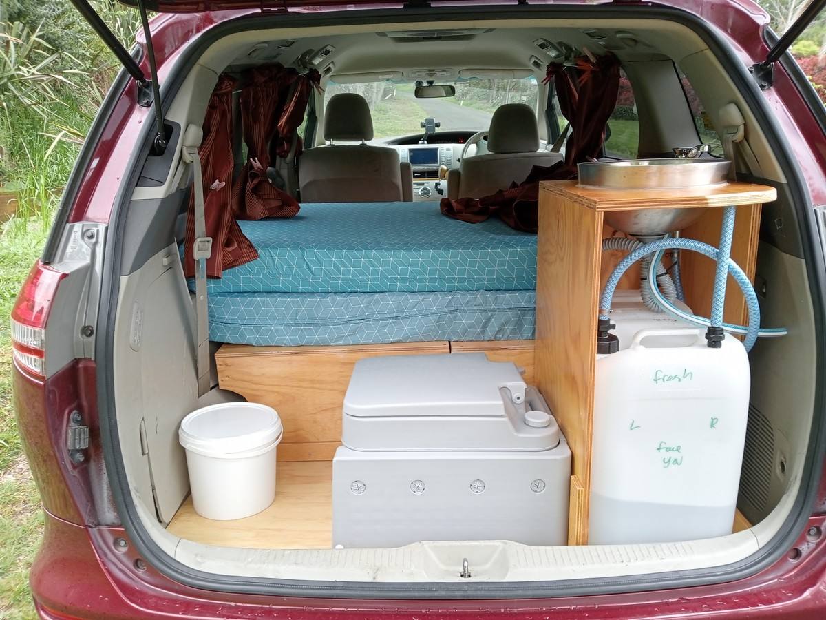 Tailgate open on the JAK653 campervan, showing the bed, portable toilet, sink unit and water container